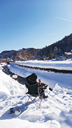 平成23年に昭和村に移住した長谷川さん。自宅裏で冬の絶景を前にコーヒーブレイクしている風景